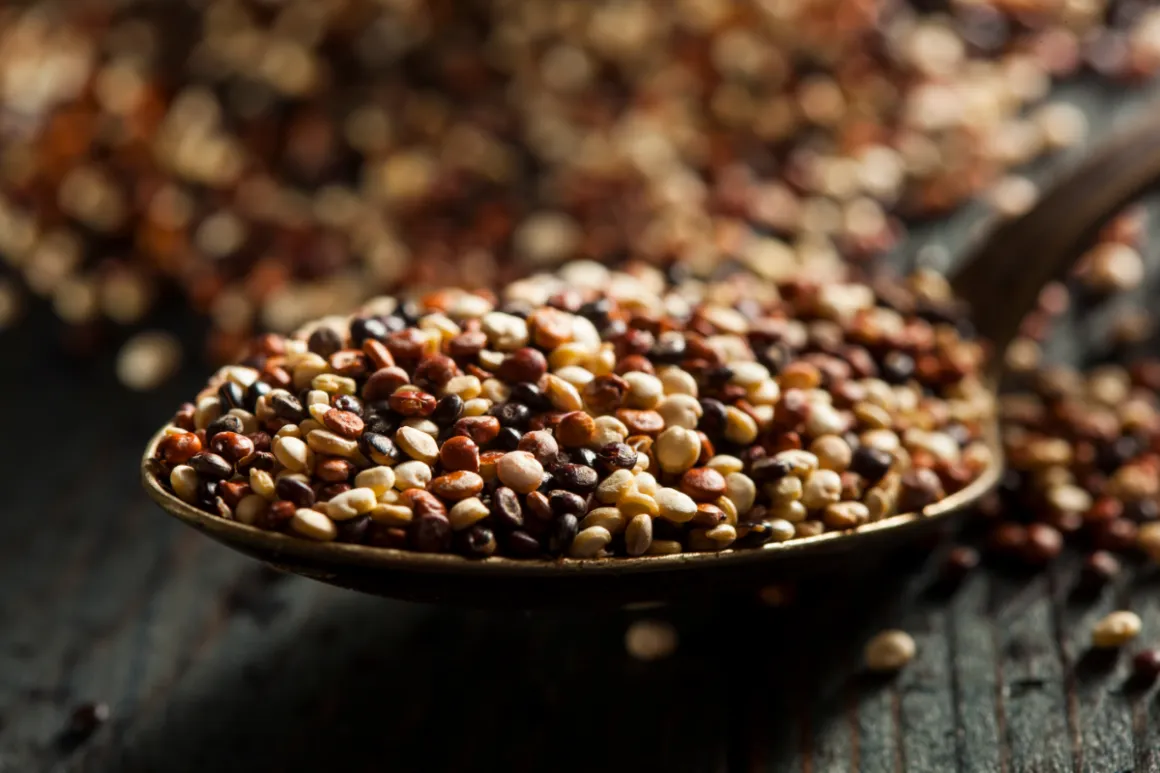 Wooden spoon with quinoa seeds on wooden table