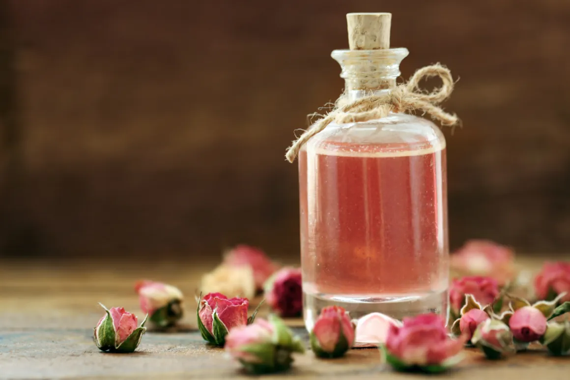 精緻的玻璃瓶裝著液體以及旁邊圍繞的玫瑰花瓣