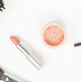 Lipstick and a peach colored beverage on a white surface