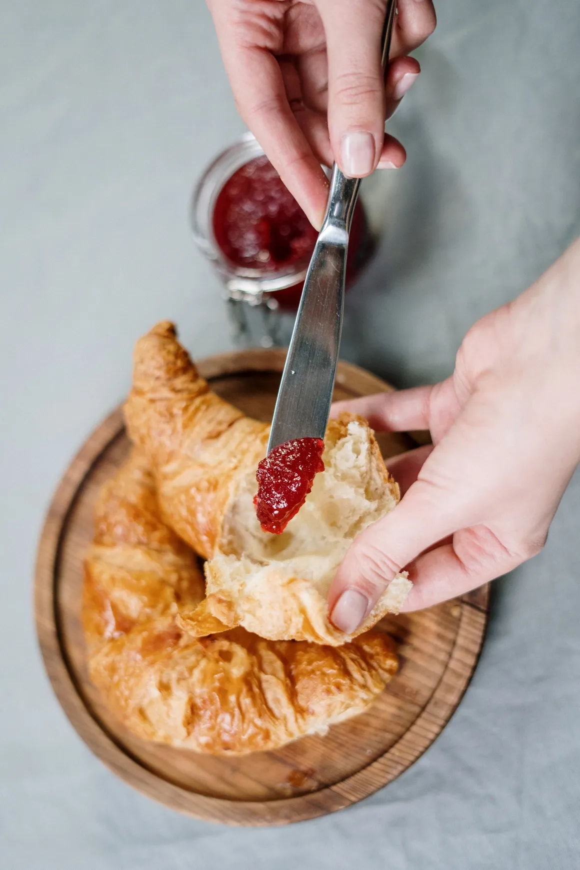 Jam being spread on a croissant