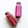 Two bottles with pink filling on white surface