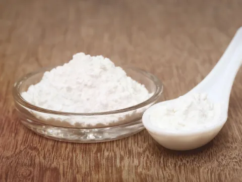 A spoon a glass dish with a fine white powder