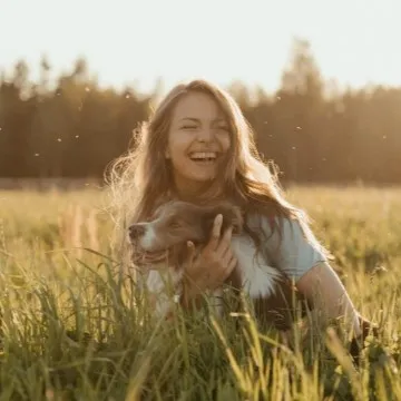 在草地上有個很開心的女生抱著她的狗狗