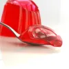 A spoon holding a red edible jelly