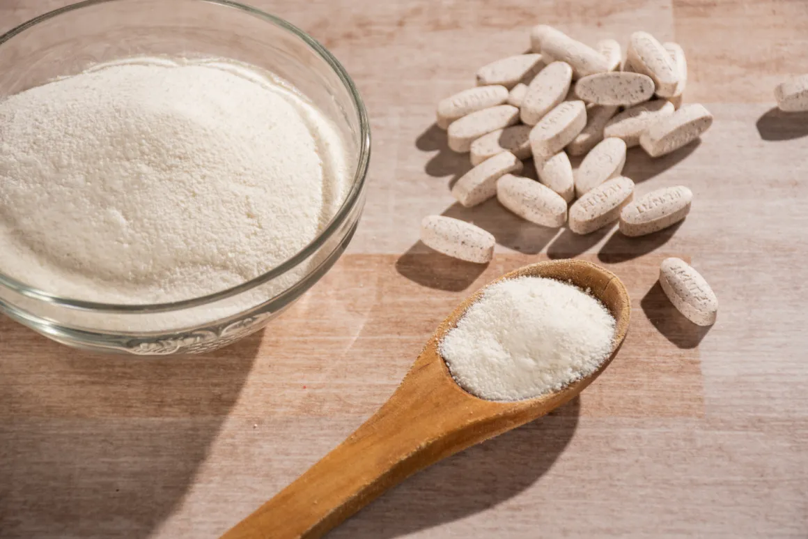 A wooden spoon with powder next to some pills and a bowl with fine powder