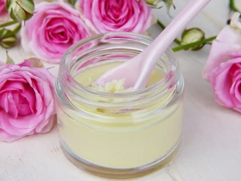 A jar of shea butter surrounded by some roses