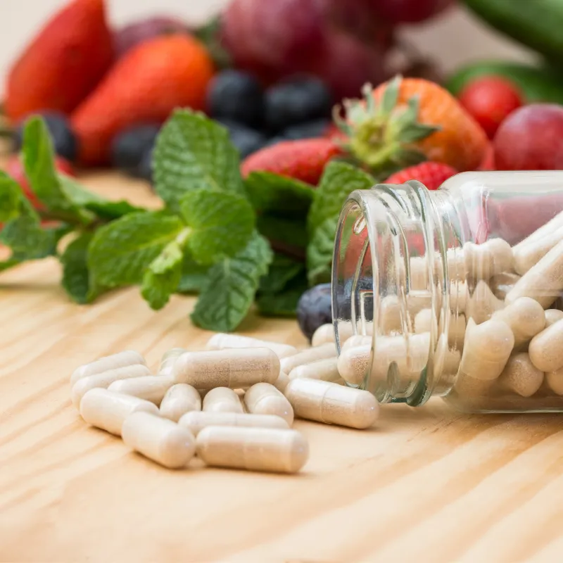 Capsules in front of some fruits and herbs