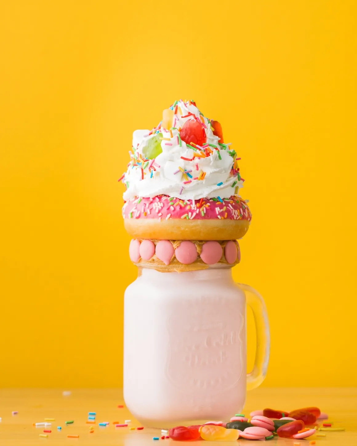 Jar with milkshake topped with colorful donuts and sprinkles