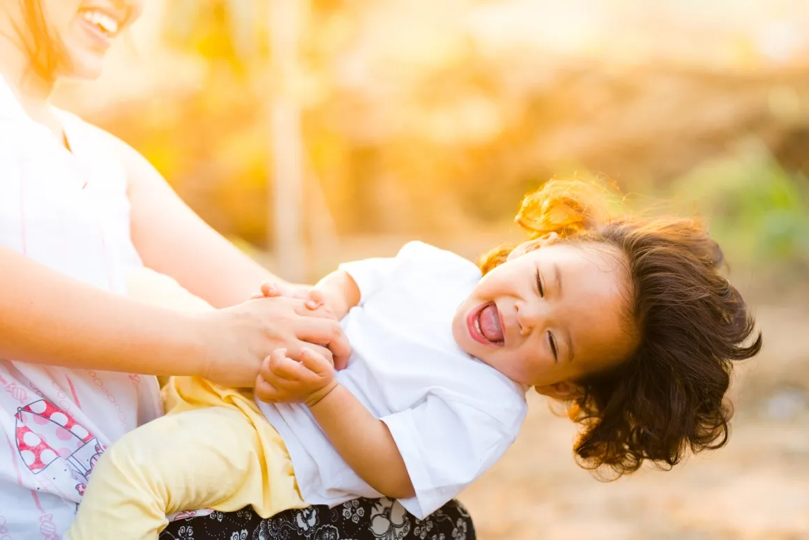 Smiling woman lifting up a baby