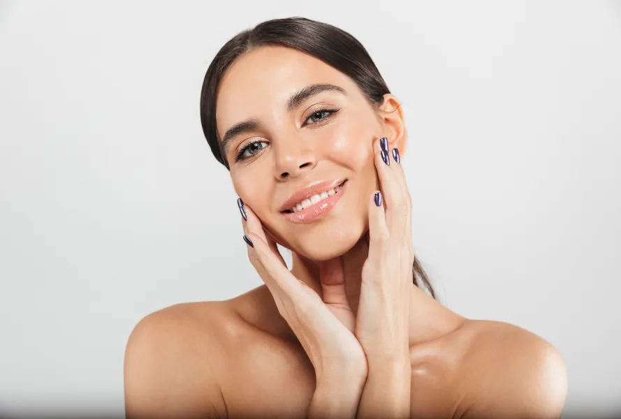 Smiling woman with smooth skin putting her hands on her cheeks