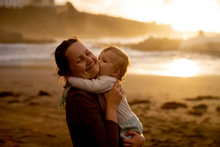 Mother at the beach holding her toddler and smiling