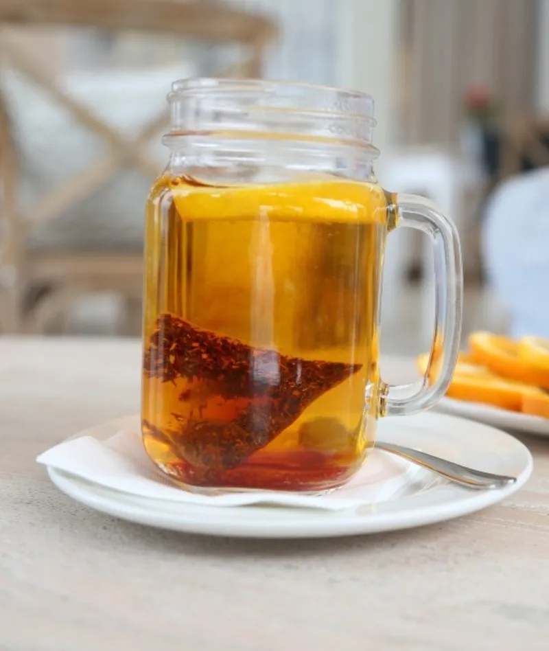 Glass with tea and teabag inside on table