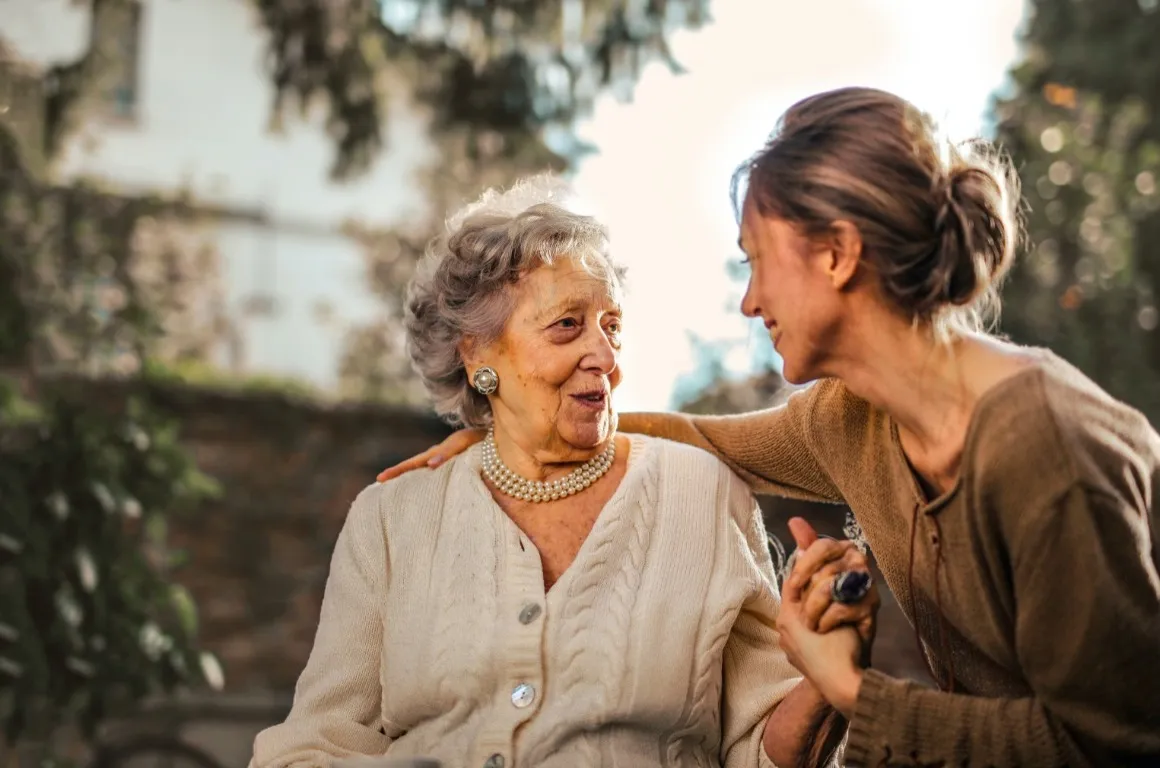 Woman holding the hand of an elderly woman and putting her arm around her