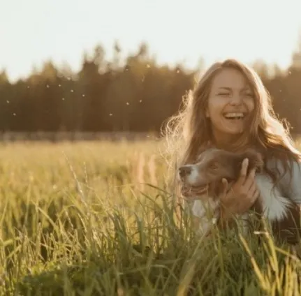 在草地上有個很開心的女生抱著她的狗狗