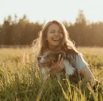 在草地上有個很開心的女生抱著她的狗狗