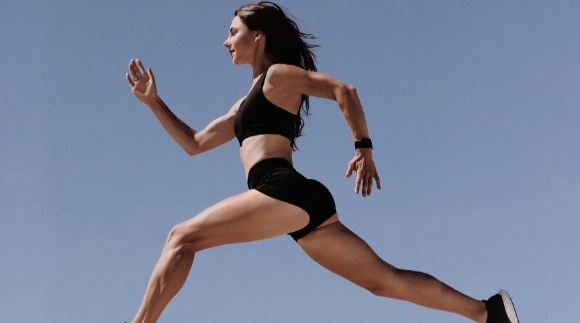 Athletic woman in sports attire running with a long stride