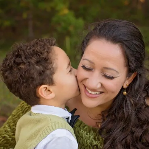 Young child kissing his smiling mother on the cheek