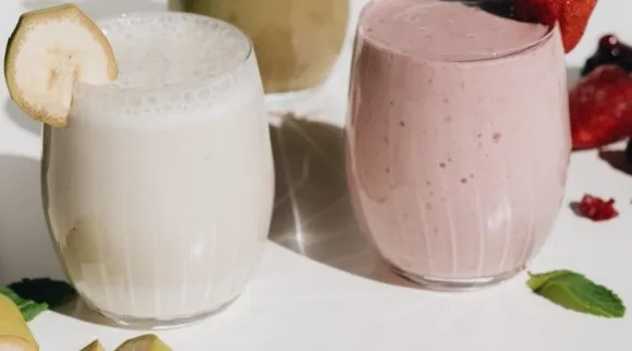 Two differently colored protein shakes decorated with fruits