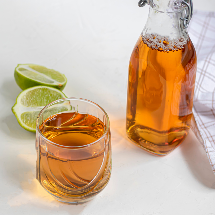 Elegant glass with golden brownish beverage in front of sliced lime