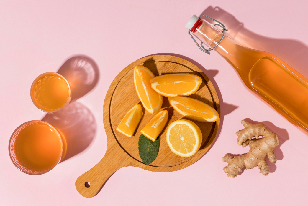 Sliced lemons on a wooden board next to a bottle of kombucha