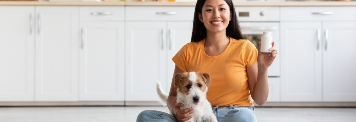 Image of a woman with her dog holding a vitamin bottle.